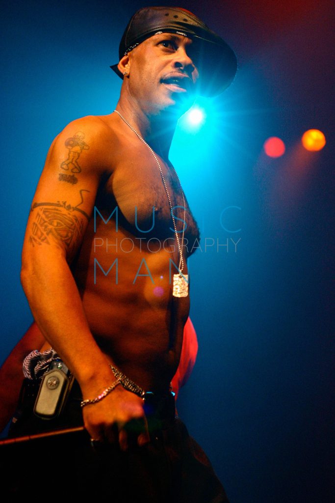 Hip-hop artist Guru of Gang Starr performing live and shirtless on stage under blue spotlights at the London Astoria, photography by Music Man Studio.
