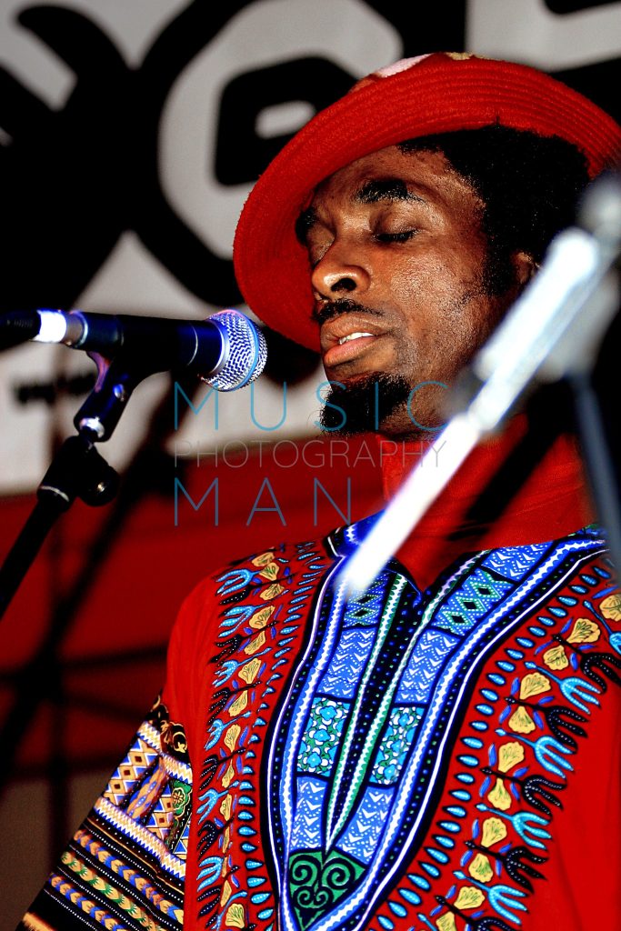 Detroit soul legend Amp Fiddler performing in a colorful dashiki and red hat live on stage at the Jazz Café in London, photography by Music Man Studio.