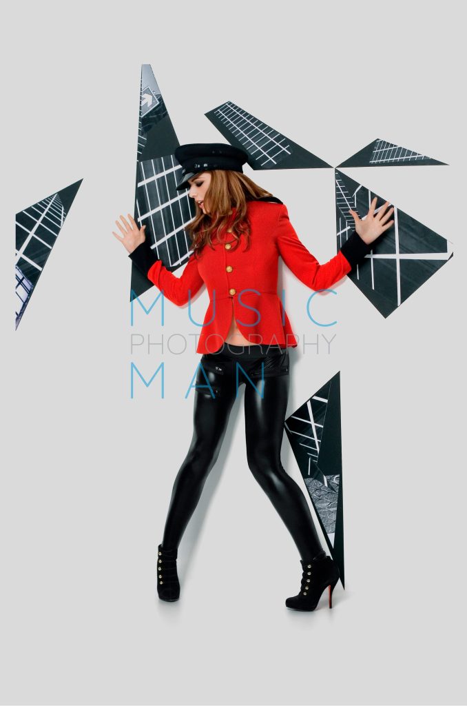 Singer Cheryl Cole posing in an iconic red military jacket and black captain hat on the studio set of her Fight for This Love music video, photography by Music Man Studio.