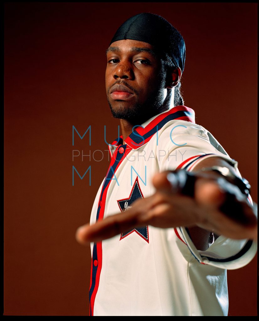 R&B soul artist Dwele reaching his hand out toward the camera during an exclusive Echoes Magazine cover studio portrait session, photography by Music Man Studio.