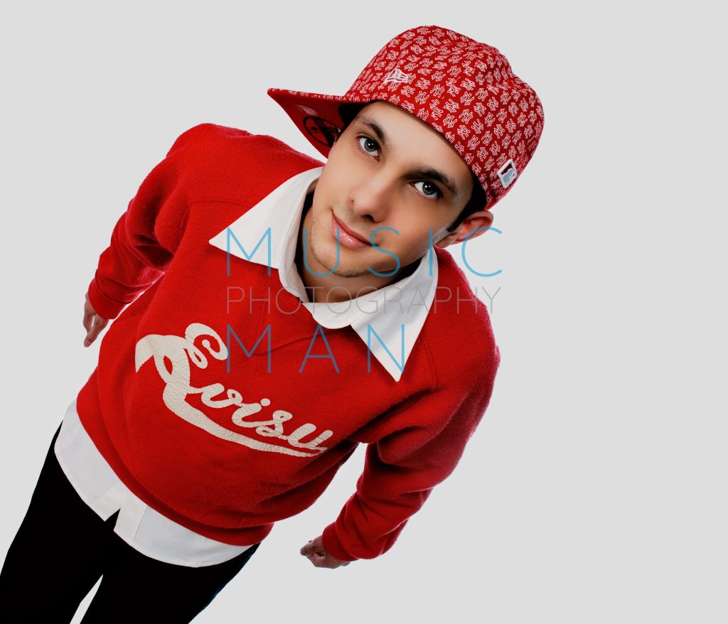 Magician Dynamo wearing a red Evisu script logo sweatshirt and tilted red New Era baseball cap during an exclusive high-angle Clerkenwell studio portrait session, photography by Music Man Studio.