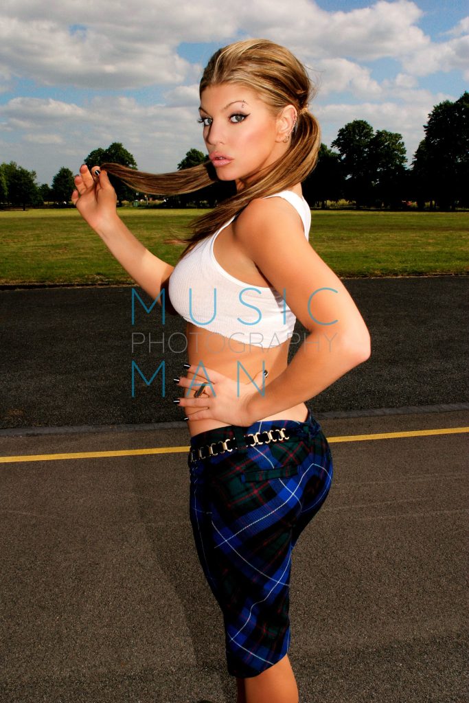 Singer Fergie posing in a white crop top and blue tartan plaid trousers on the tarmac during her London Bridge music video shoot, behind the scenes photography by Music Man Studio.