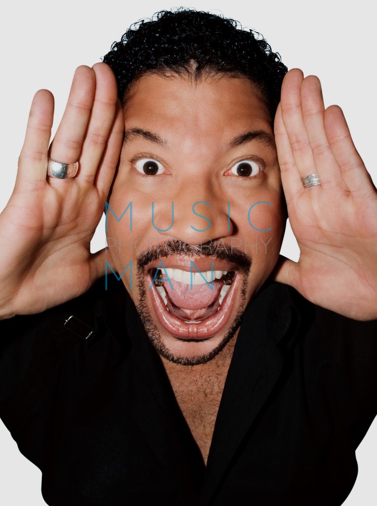 Singer Lionel Richie holding his hands up to his face with a wide expression during an exclusive Blues and Soul Magazine front cover studio portrait session at the Dorchester Hotel, photography by Music Man Studio.