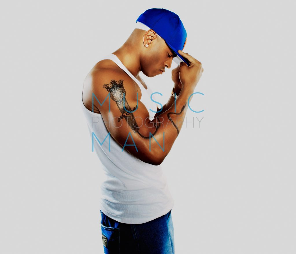 Hip-hop icon LL Cool J posing for the front cover of Blues and Soul Magazine, showing his microphone tattoo and adjusting a blue baseball cap, studio portrait photography by Music Man Studio.