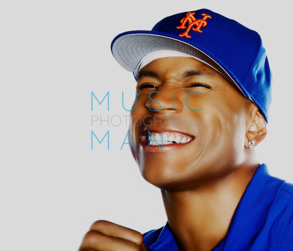 Hip-hop artist LL Cool J laughing and smiling during a close-up studio portrait session wearing a blue New York Mets baseball cap, photography by Music Man Studio.