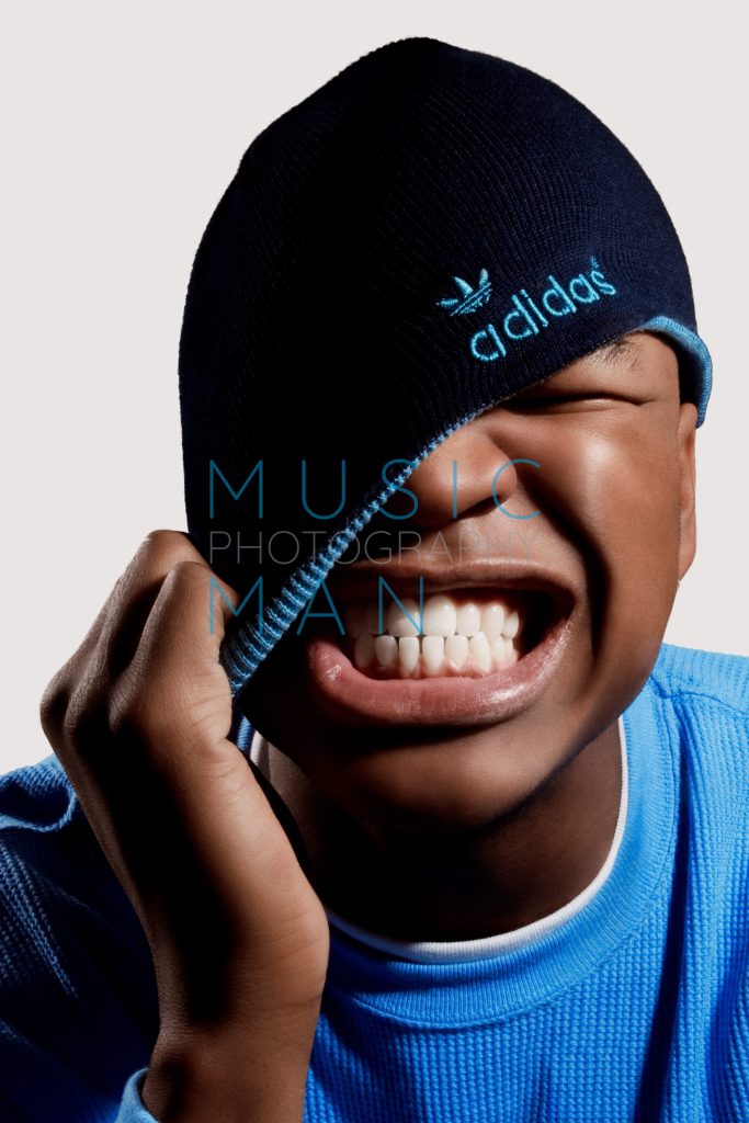 R&B singer Ne-Yo displaying a wide grin while pulling a blue Adidas beanie with a teal logo down over his eyes during his official Blues and Soul Magazine front cover studio portrait session, photography by Music Man Studio.