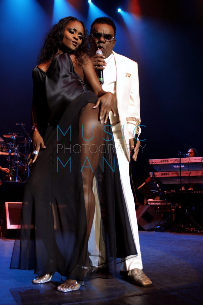 Ronald Isley of the Isley Brothers performing live in a white suit with a cane alongside a dancer on stage at the Royal Albert Hall in London, photography by Music Man Studio.