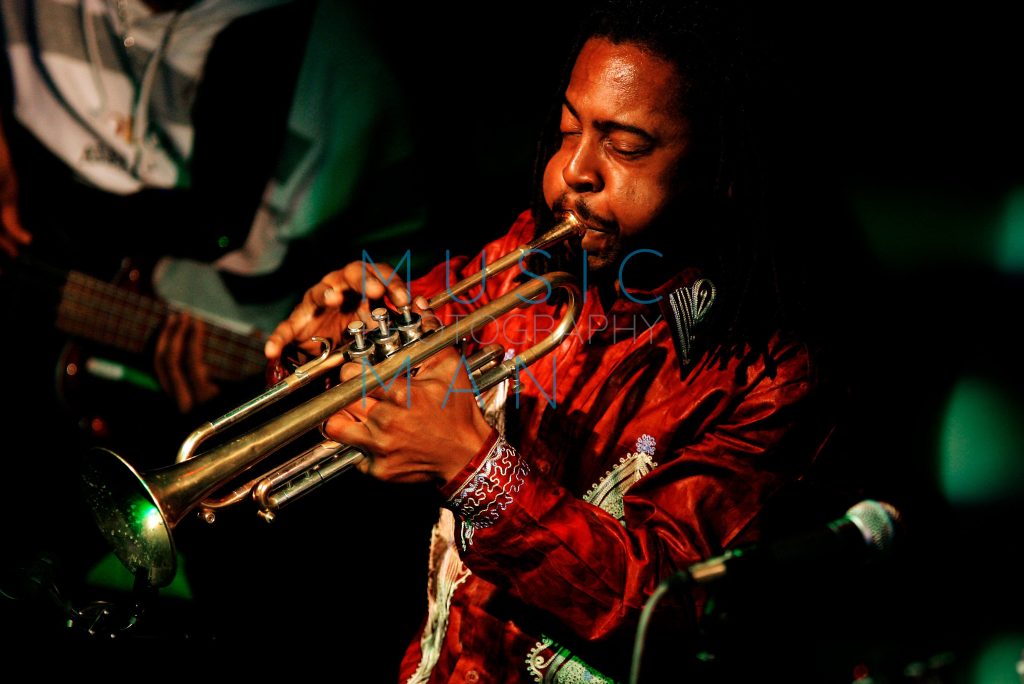 Jazz musician Roy Hargrove playing a trumpet live with a bass guitarist in the background at the Jazz Café in London, photography by Music Man Studio.